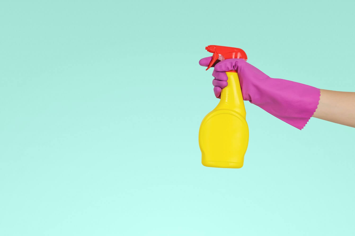 Una mano con un guante morado sujeta un spray amarillo